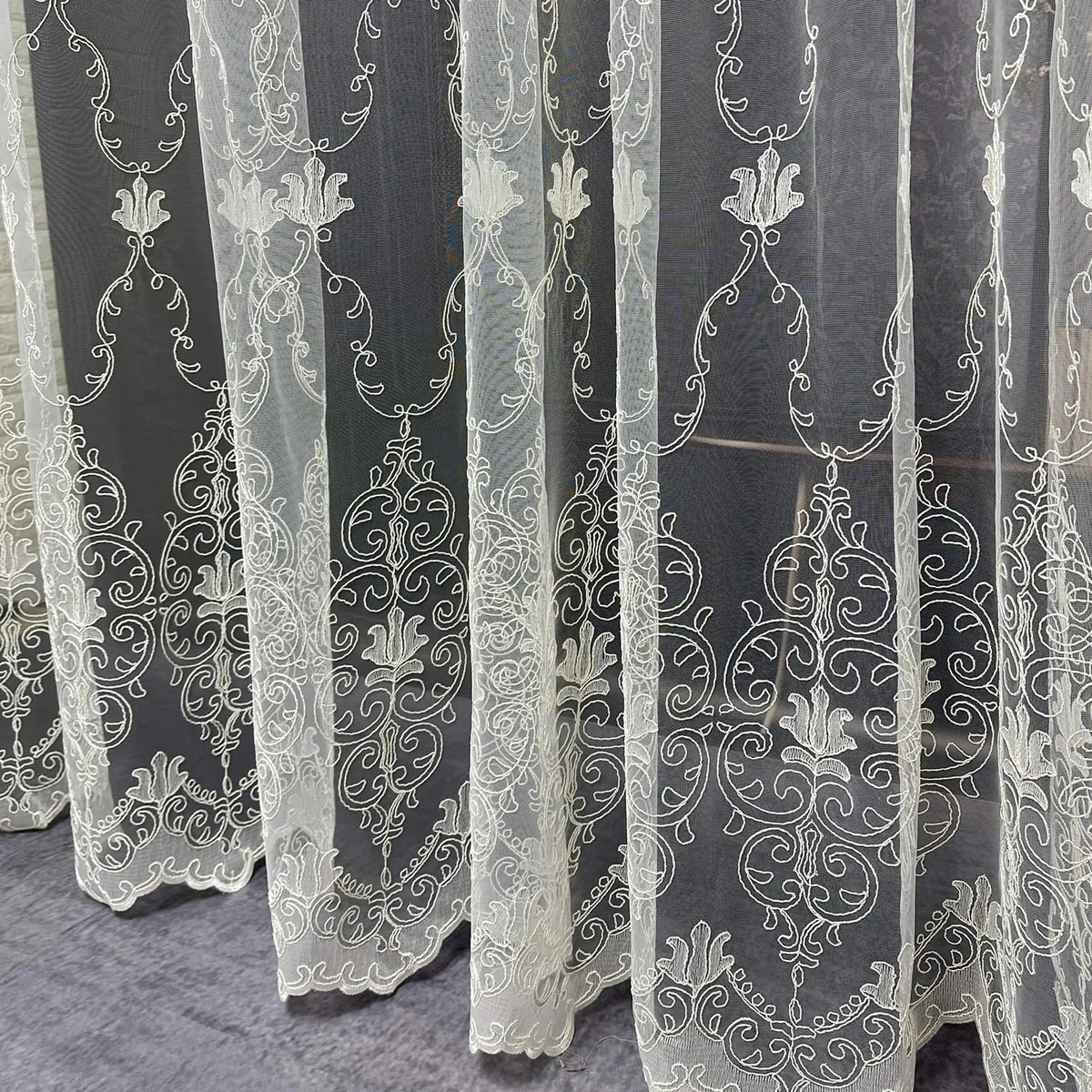 White embroidered lace curtains on a dark background