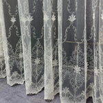 White embroidered lace curtains on a dark background