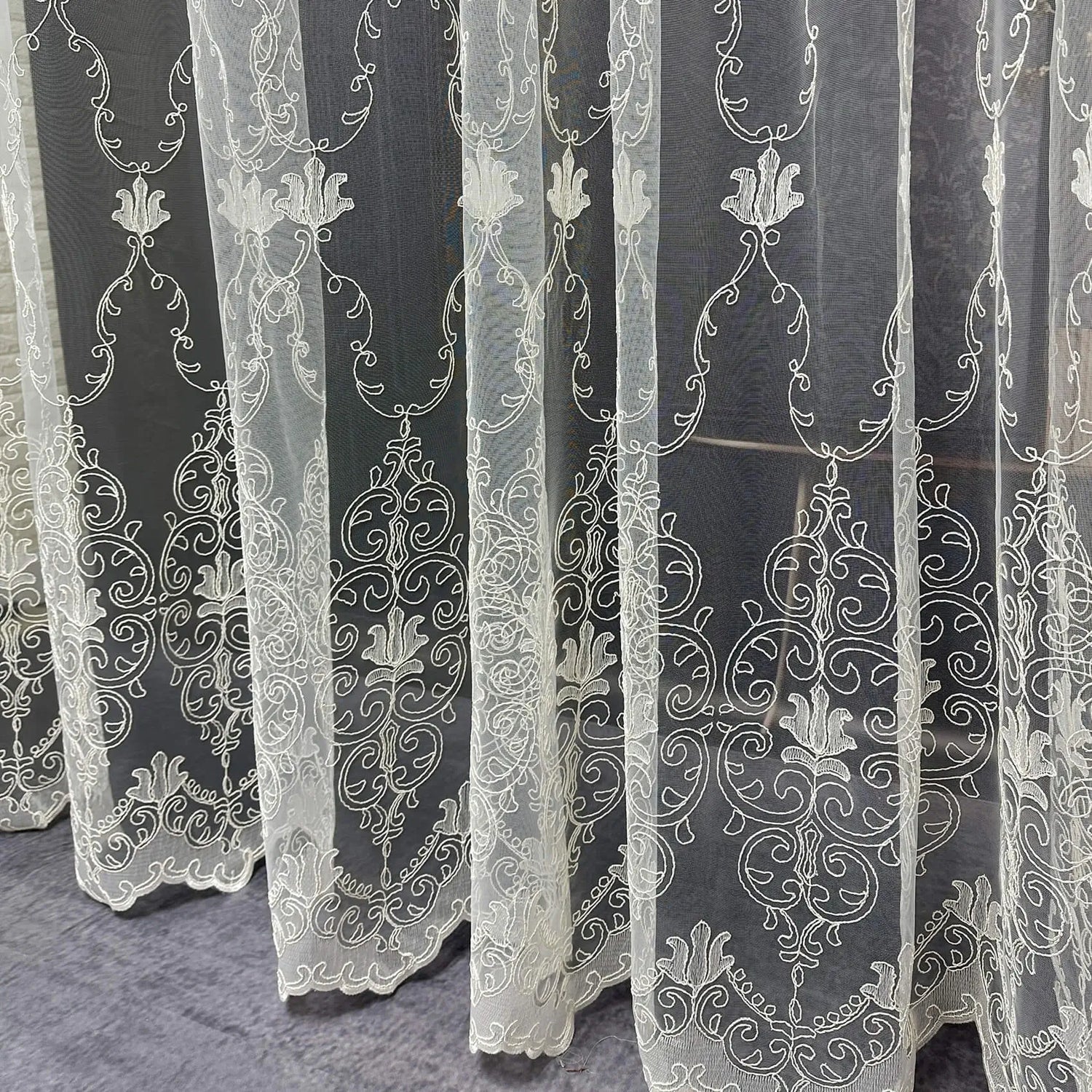 White embroidered lace curtains on a dark background