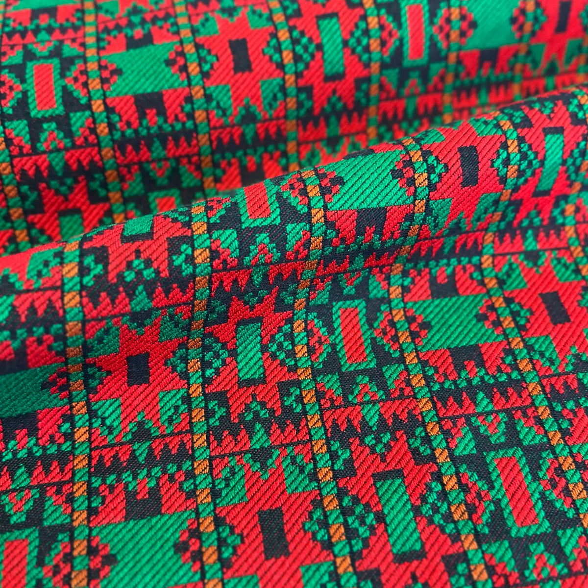 Close-up of fabric with a vibrant geometric pattern in red, green, and black.
