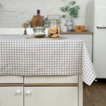 Kitchen island with a checkered tablecloth, jars, and cookies.