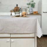 Kitchen island with a checkered tablecloth, jars, and cookies.