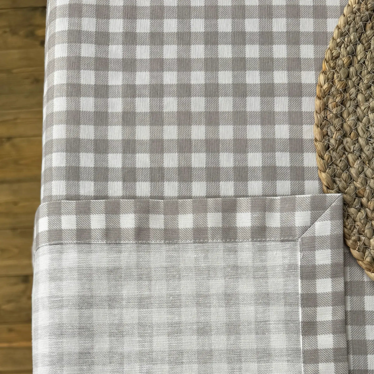 Gray and white checkered tablecloth on a wooden table with a woven placemat.