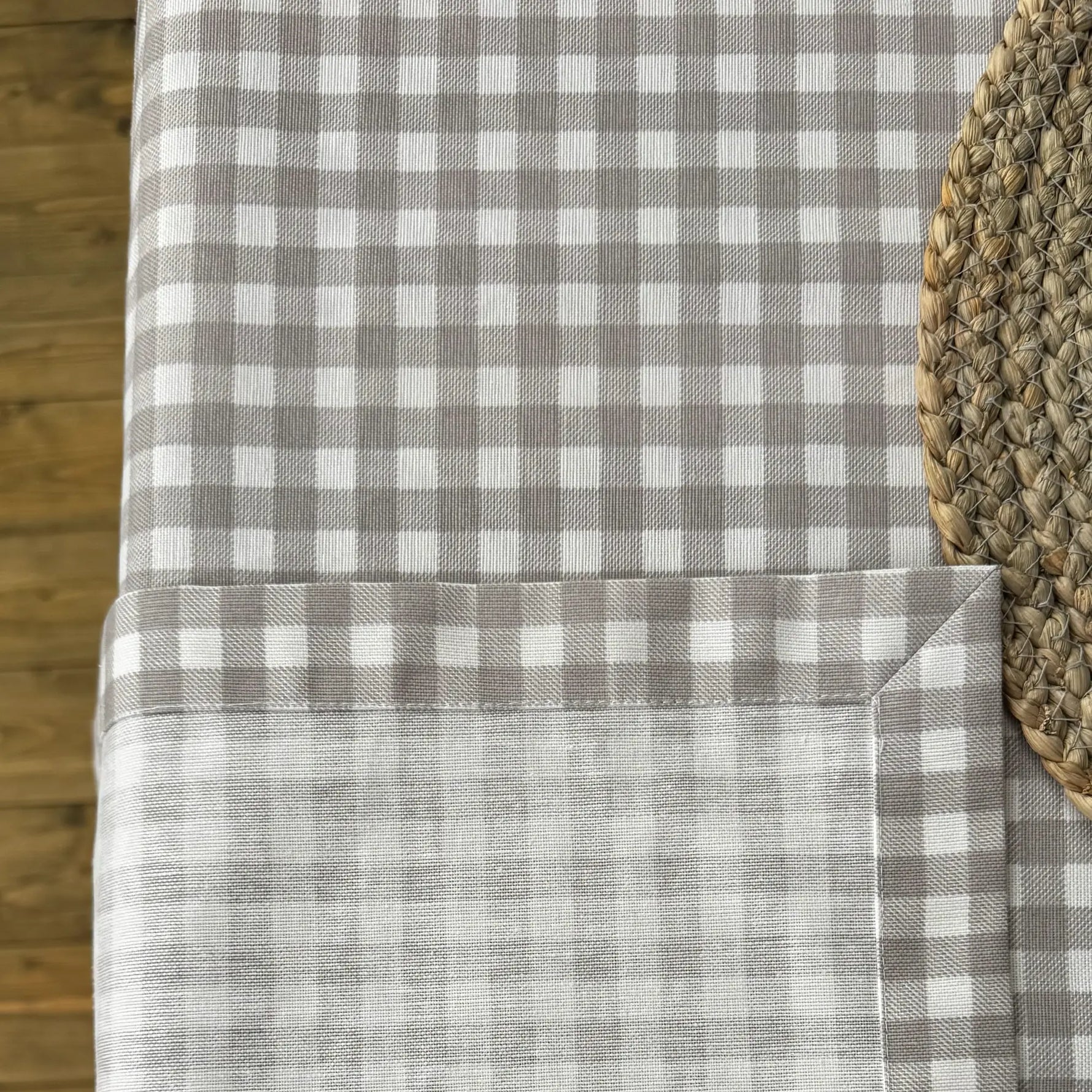 Gray and white checkered tablecloth on a wooden table with a woven placemat.