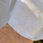 Close-up of a hand holding white fabric with a textured pattern.