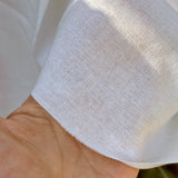 Close-up of a hand holding white fabric with a textured pattern.