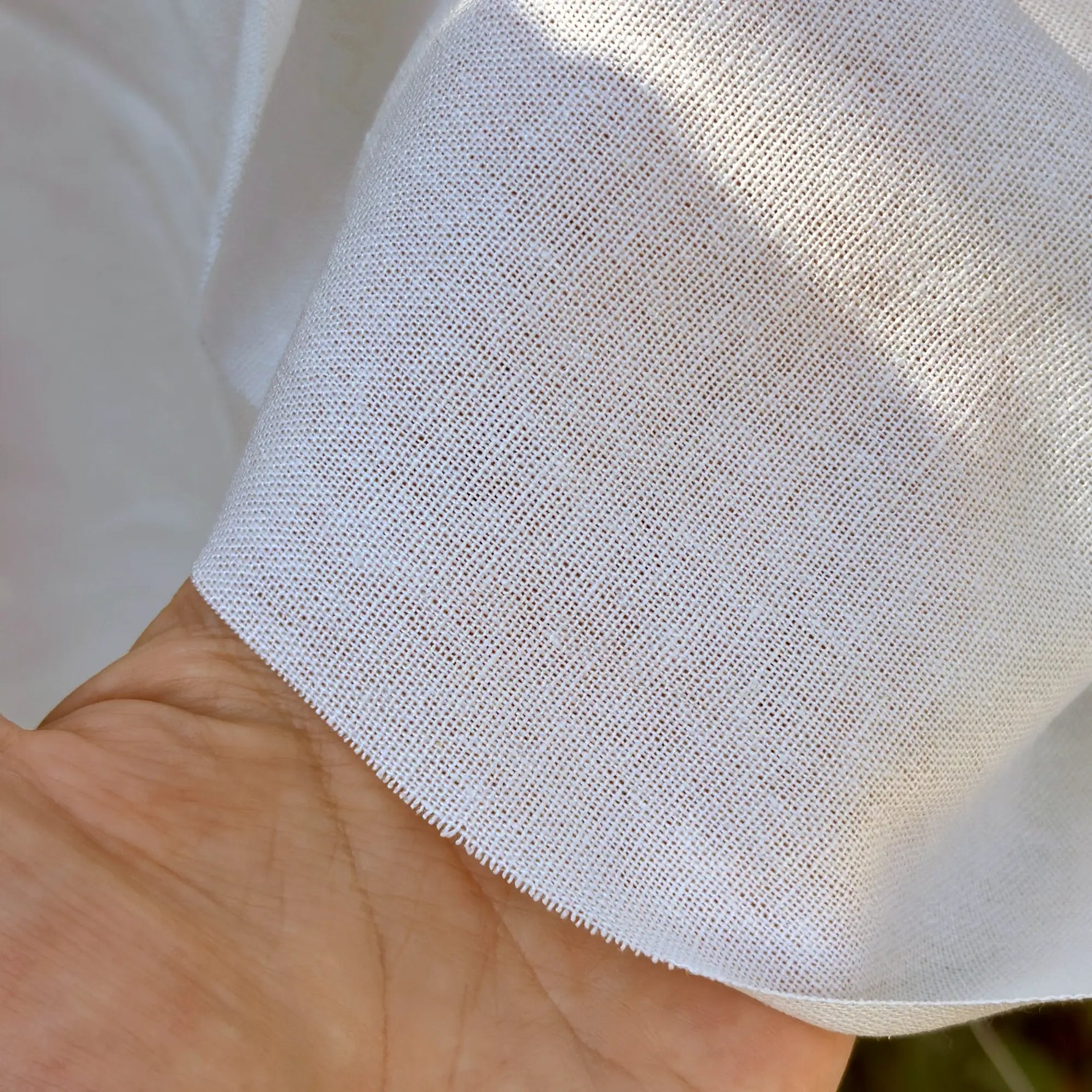 Close-up of a hand holding white fabric with a textured pattern.