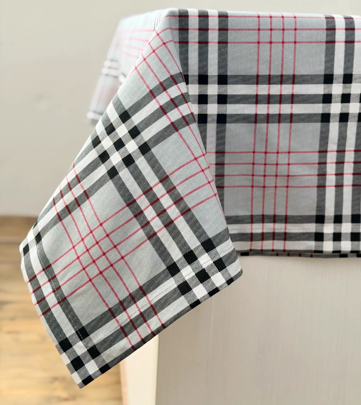 Plaid tablecloth with red, black, and white pattern on a neutral background