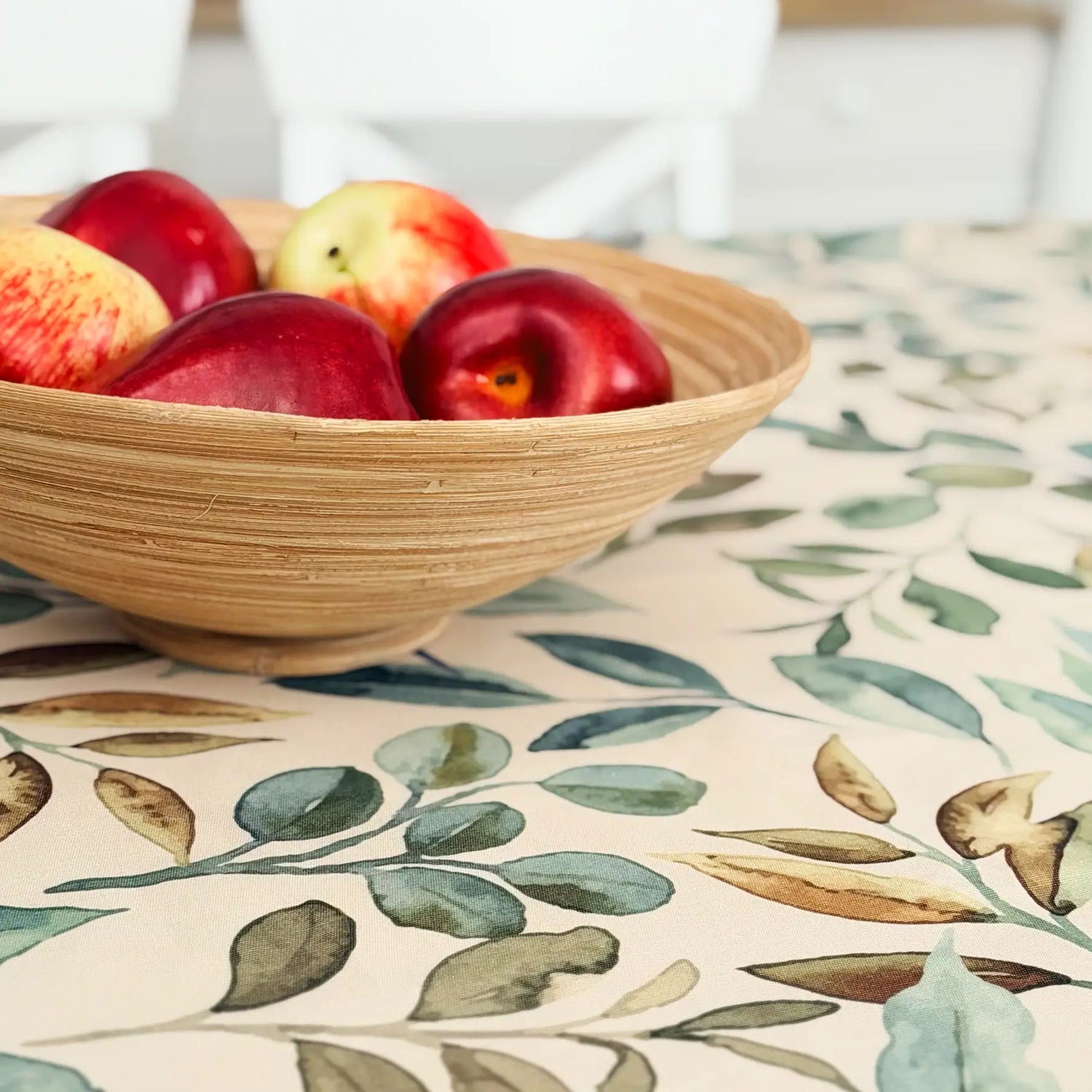 Wooden bowl with apples on a tablecloth with leaf pattern