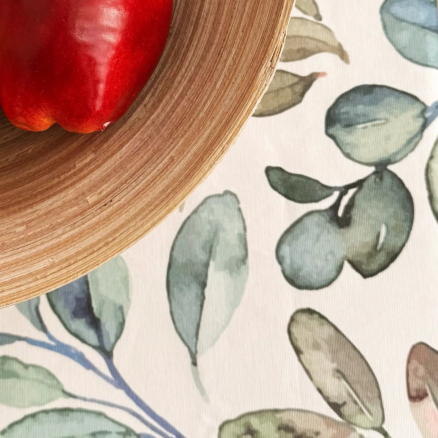 Red bell pepper on a wooden plate with a leaf-patterned tablecloth
