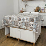 Patterned tablecloth on a kitchen island with a white brick wall background