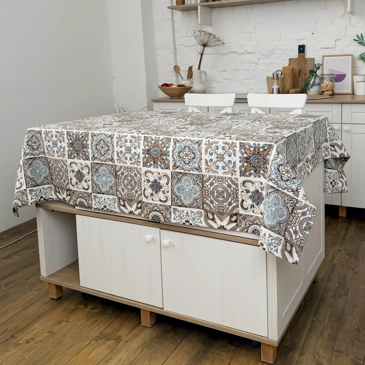Patterned tablecloth on a kitchen island with a white brick wall background