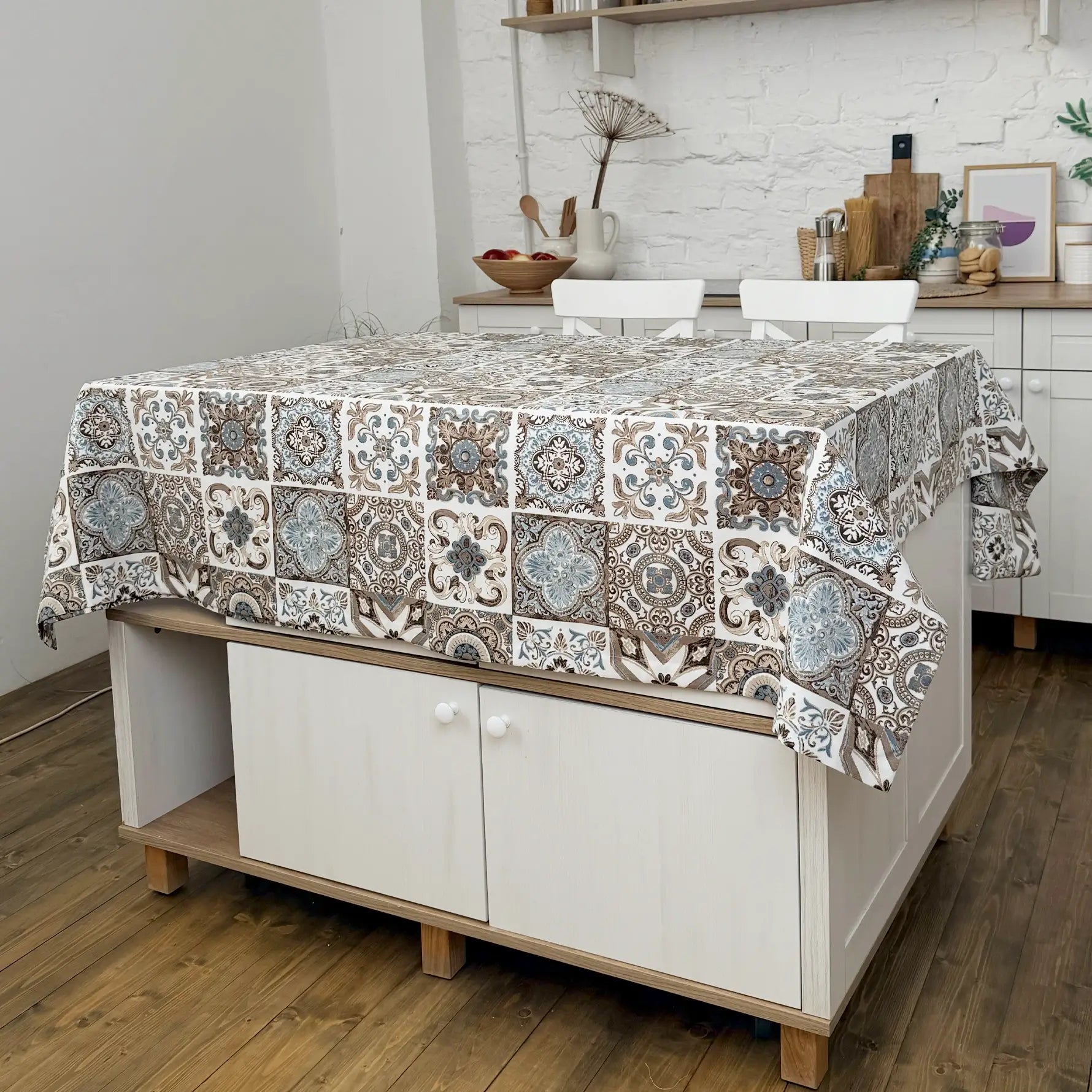 Patterned tablecloth on a kitchen island with a white brick wall background