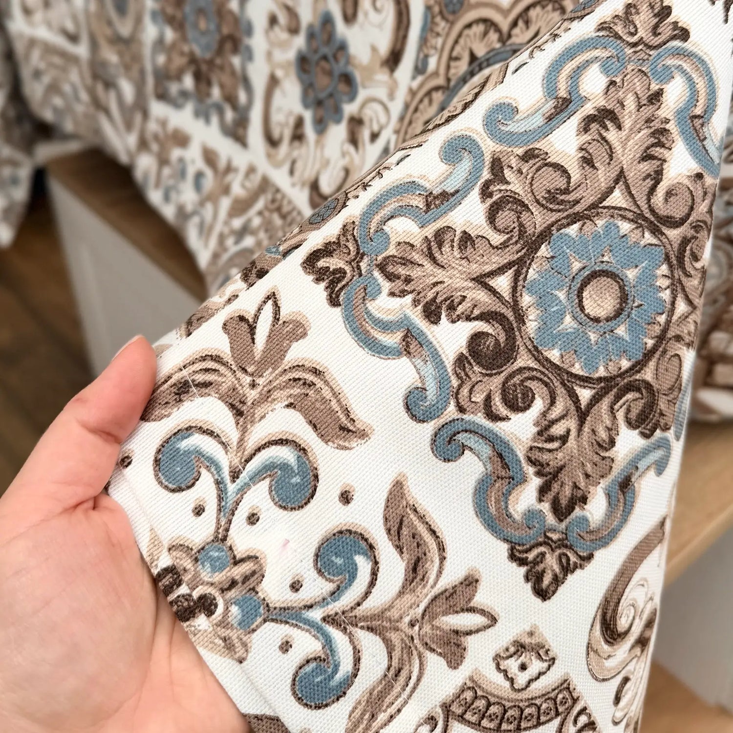 Patterned fabric held by a hand with a blurred background
