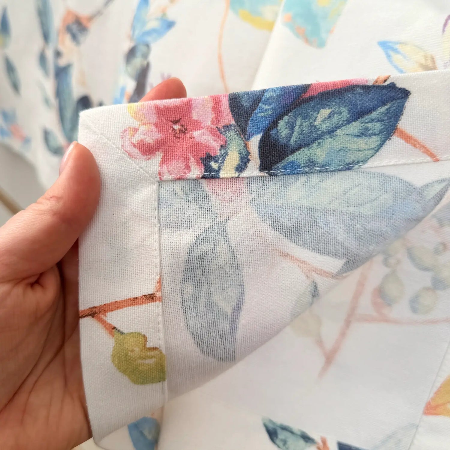 Close-up of a hand holding floral fabric with a colorful pattern.