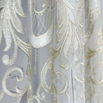 Close-up of decorative fabric with intricate gold patterns on a light gray background