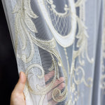 Decorative fabric with gold embroidery held by a hand against a dark background