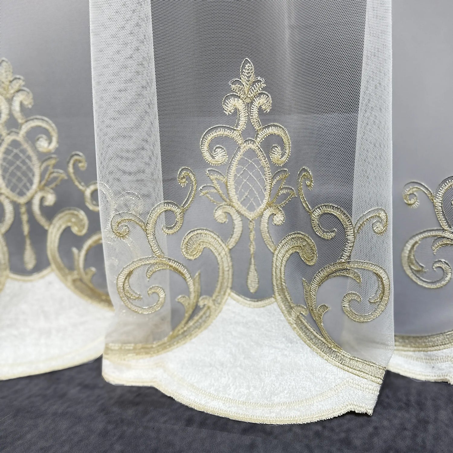 Decorative sheer curtain with gold embroidery on a dark background