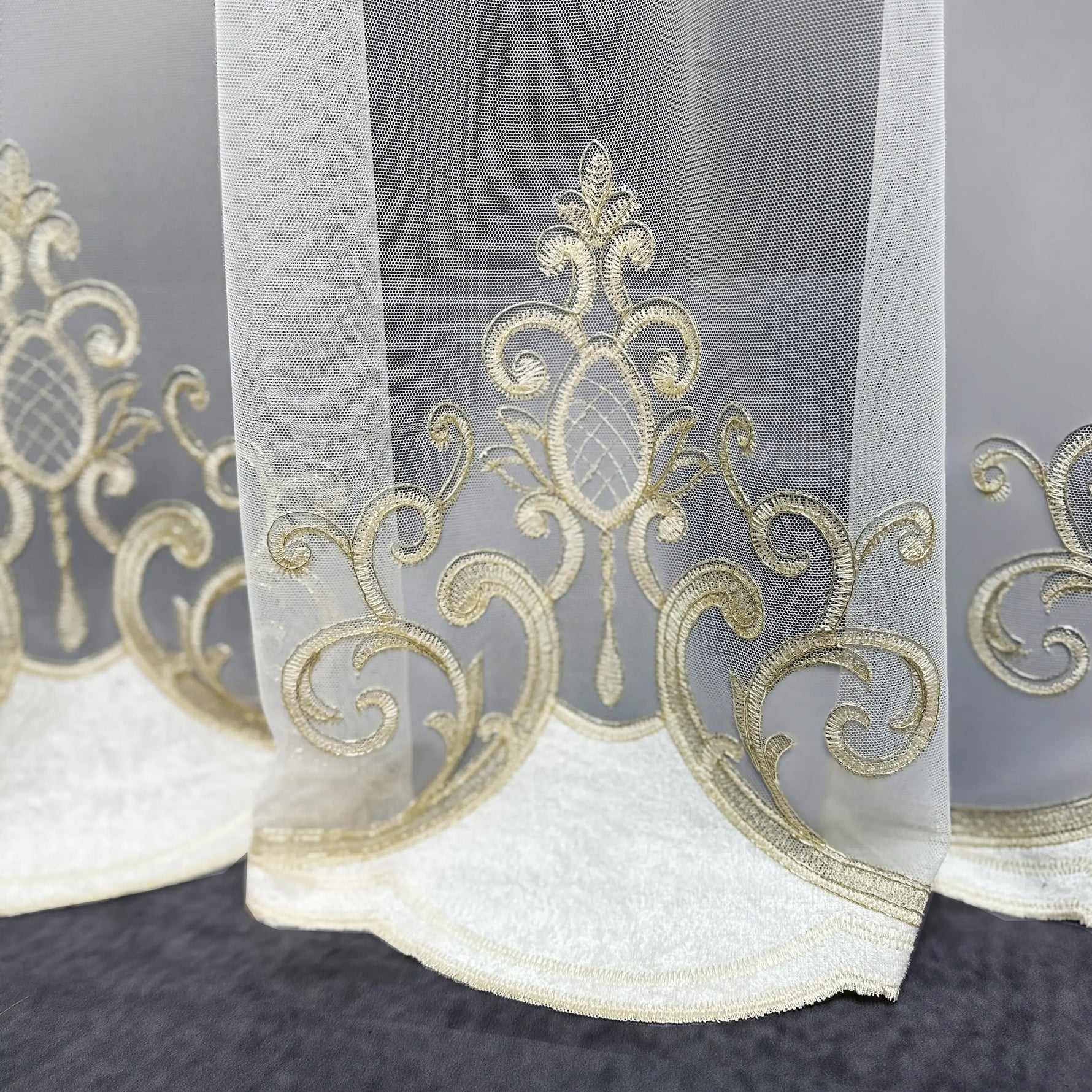Decorative sheer curtain with gold embroidery on a dark background