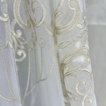 Close-up of a white fabric with gold embroidery on a blurred background