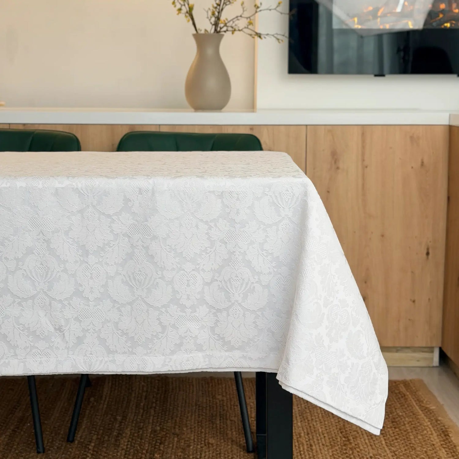 Dining table with a white patterned tablecloth in a kitchen setting.