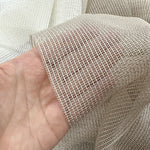 Close-up of a hand holding a piece of mesh curtains fabric.