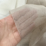 Close-up of a hand holding a piece of mesh curtains fabric.