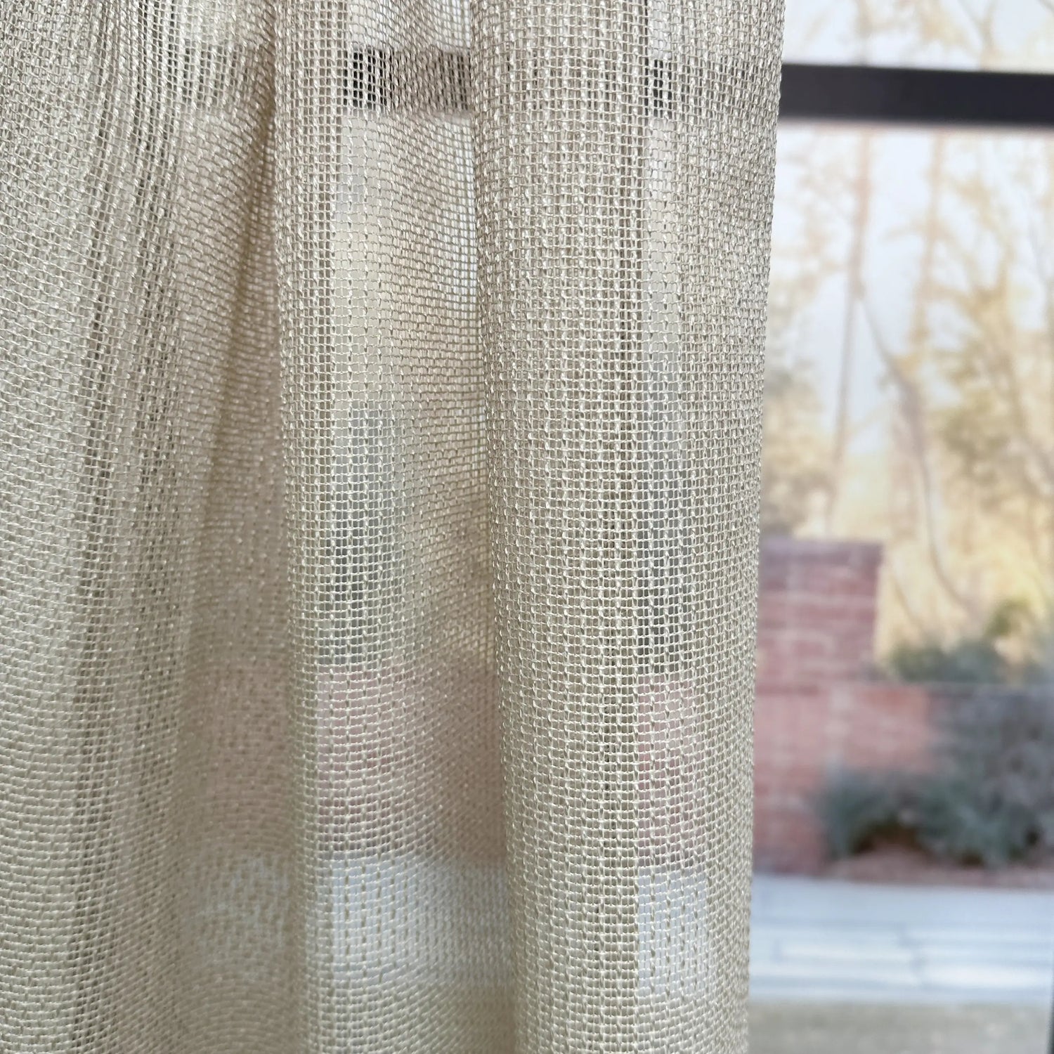 Textured beige curtain with outdoor scene in the background