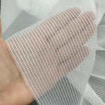 Close-up of a hand holding a piece of white mesh curtains fabric.