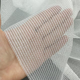 Close-up of a hand holding a piece of white mesh curtains fabric.