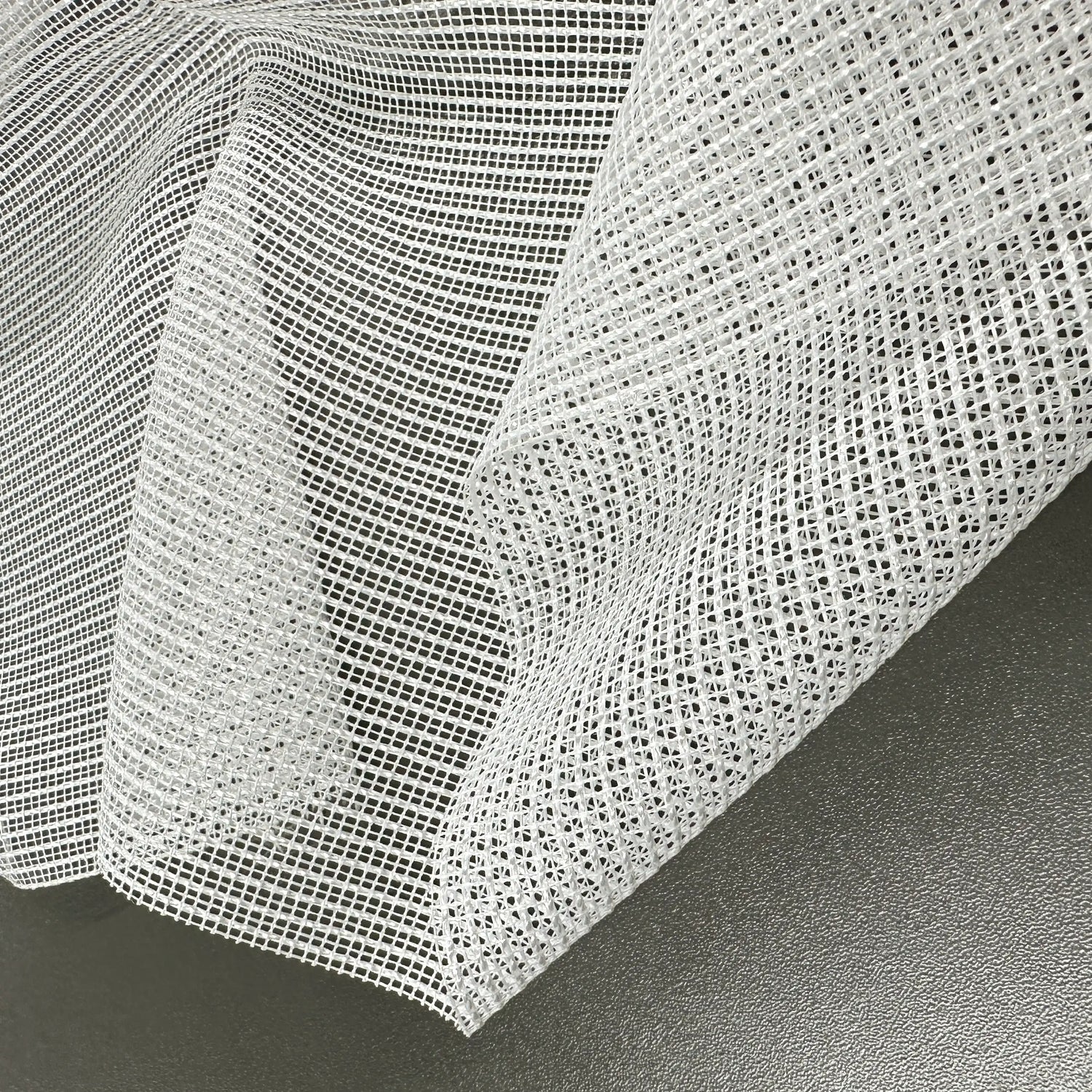 Close-up of a textured white tulle fabric on a dark surface