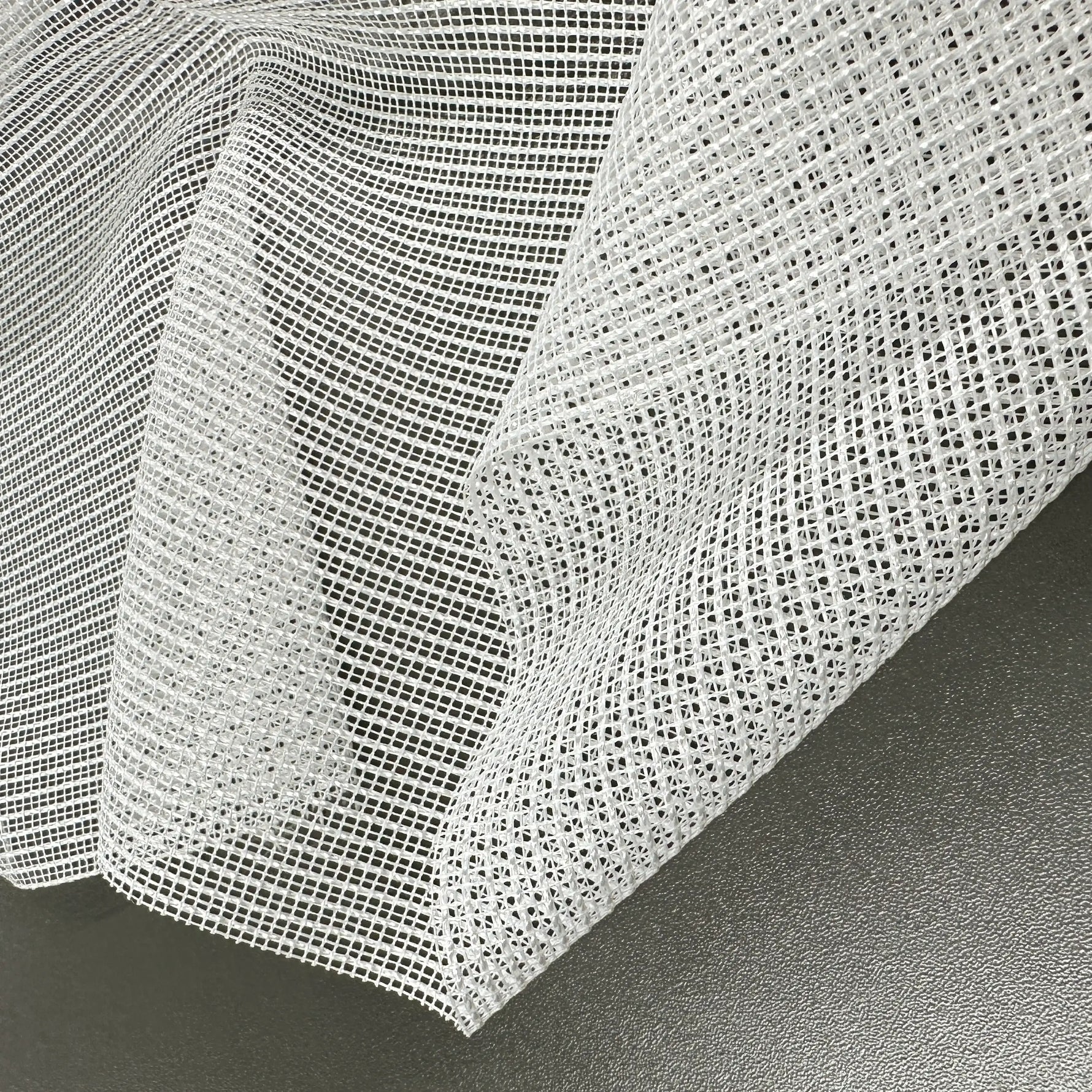 Close-up of a textured white tulle fabric on a dark surface