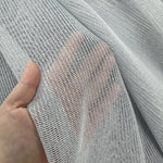 Close-up of a hand holding a piece of textured gray curtains fabric.
