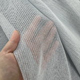 Close-up of a hand holding a piece of textured gray curtains fabric.