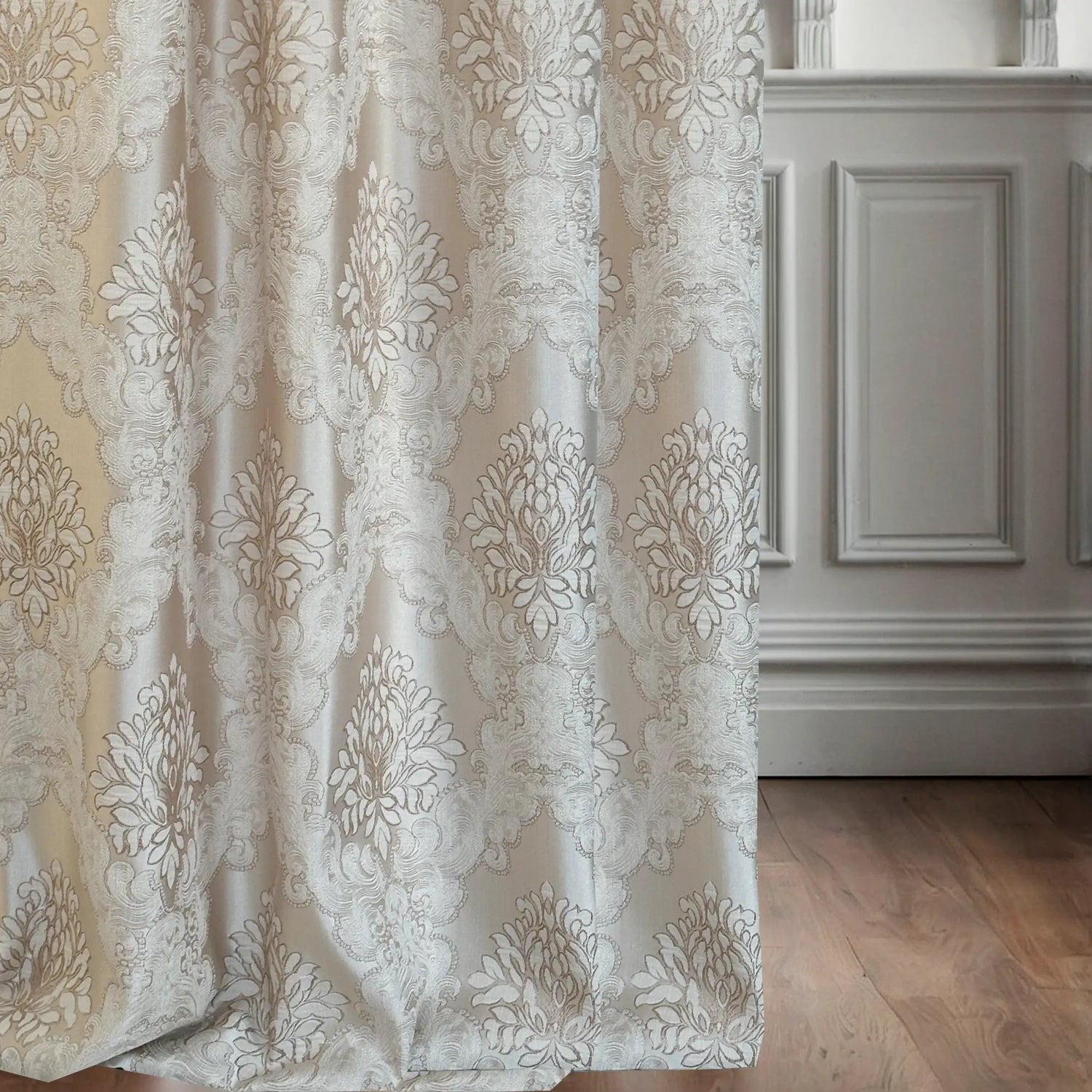Decorative curtain with intricate patterns in a room with wooden flooring and white walls.