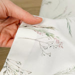 Hand holding fabric with floral embroidery
