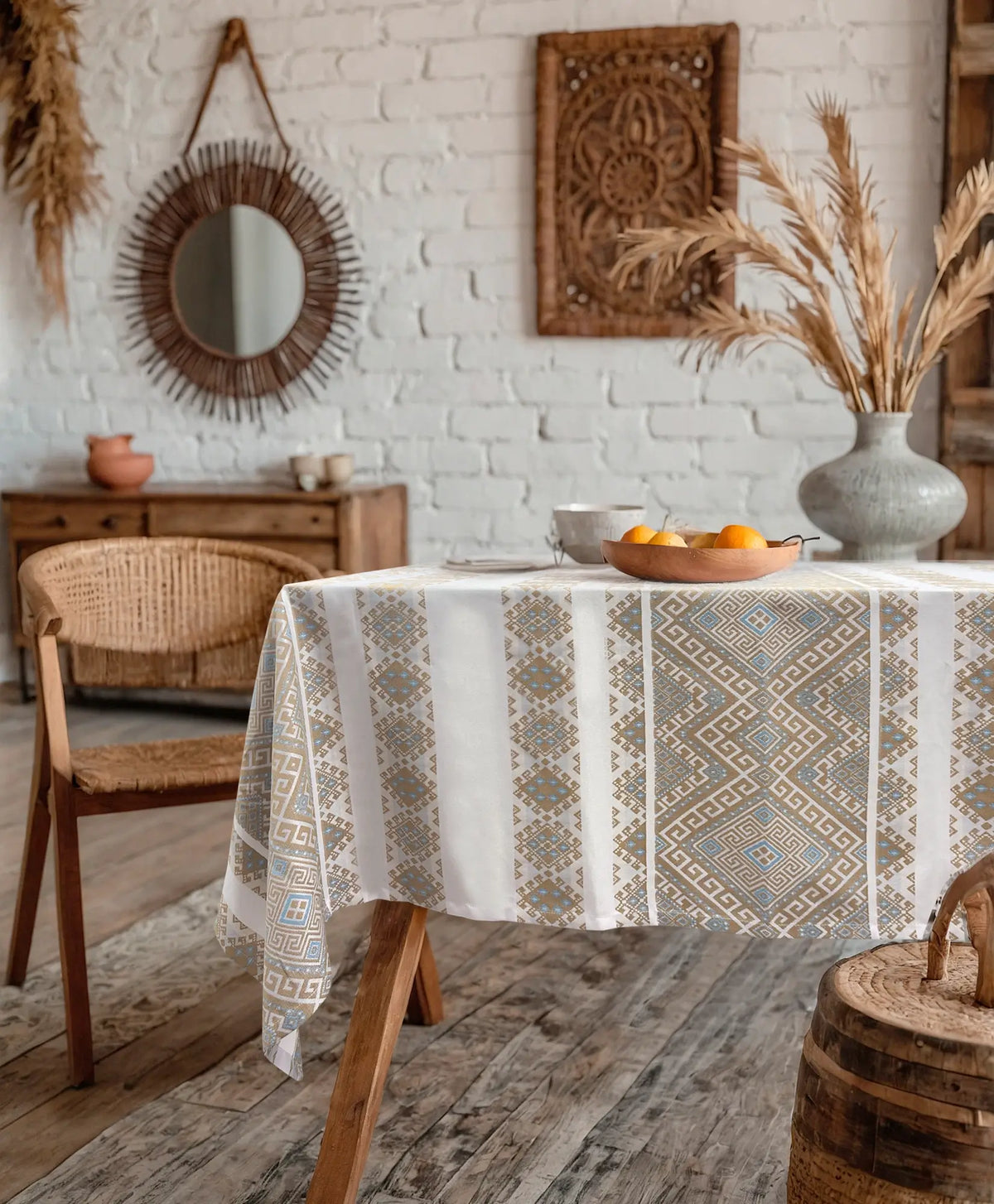 Dining room with a table covered by a patterned tablecloth, wooden chairs, and decorative elements.
