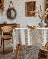 Dining room with a table covered by a patterned tablecloth, wooden chairs, and decorative elements.