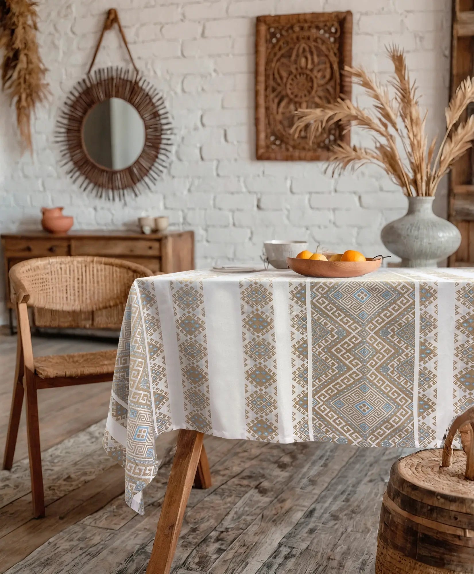 Dining room with a table covered by a patterned tablecloth, wooden chairs, and decorative elements.