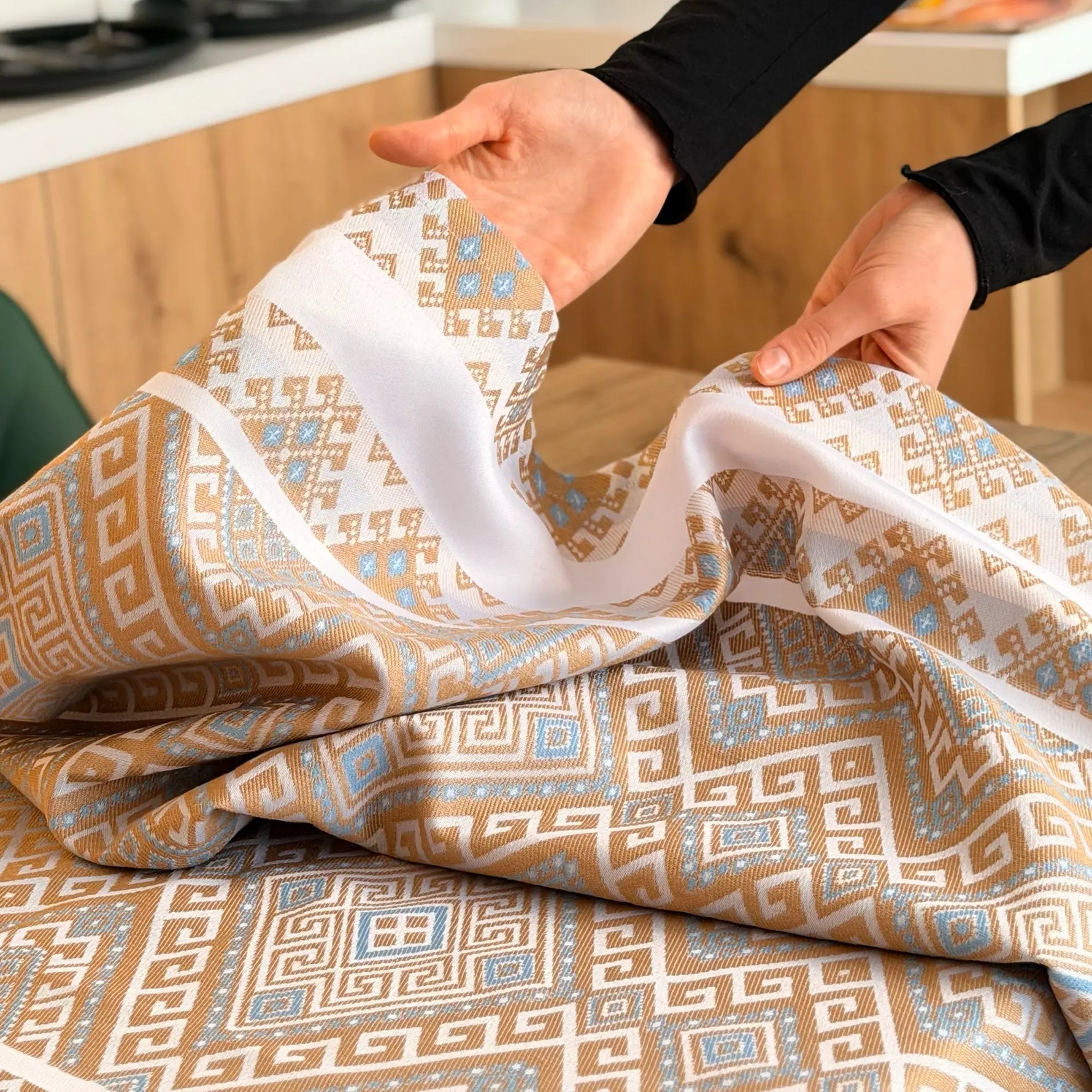 Person holding patterned fabric with geometric design in a kitchen setting